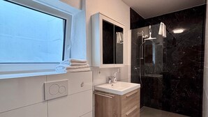 Een moderne badkamer met toilet, wastafel en douche.