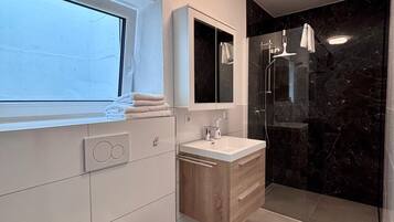 Une salle de bain moderne équipée de toilettes, d’un lavabo et d’une douche.