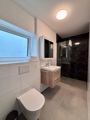 Ein modernes Badezimmer mit Toilette, Waschbecken und Dusche.