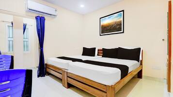 A bedroom with a bed, a window with curtains, an air conditioning unit, and a painting on the wall.