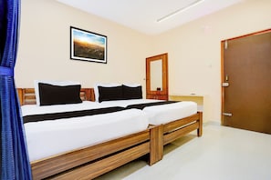 Habitació d'hotel amb un llit, una taula de nit, un mirall i una porta.