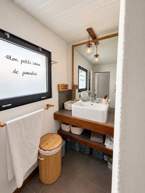 A modern bathroom with a large mirror, white sink, wooden shelves, and a white towel hanging on a wooden rack. - A tropical retreat under the Saint Martin sun (Cul-de-Sac)
