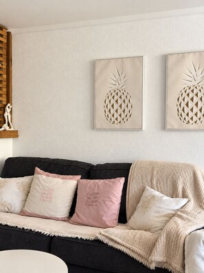 A living room with a dark-colored sofa, two cushions with text, and two wall-mounted pineapple artwork. - A tropical retreat under the Saint Martin sun (Cul-de-Sac)