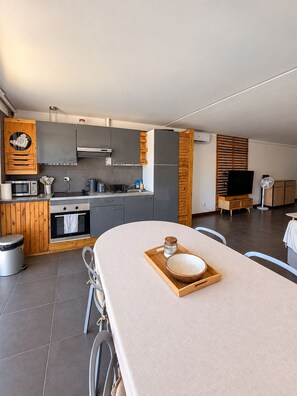 A modern kitchen with grey cabinets, a wooden cabinet with a decorative item, a microwave, and a kettle. - A tropical retreat under the Saint Martin sun (Cul-de-Sac)
