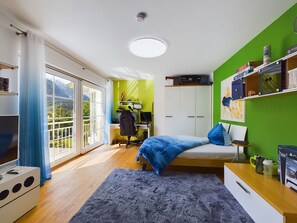 Ein Schlafzimmer mit einem Bett, einem Schreibtisch, einem Stuhl, einem Computer und einem Bücherregal.