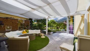 A covered outdoor seating area with a sofa, chairs, and a small table.