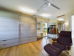 A modern interior with a wooden floor, a brown leather chair, a clothing rack, and a large closet with sliding doors.