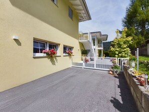 A building with a yellow facade, a gated entrance, and flower boxes on the windows.