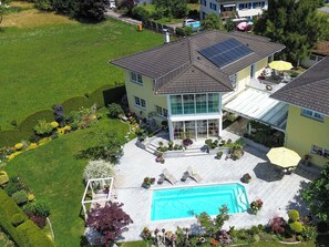 A modern two-story house with a swimming pool, solar panels, and a well-maintained garden.