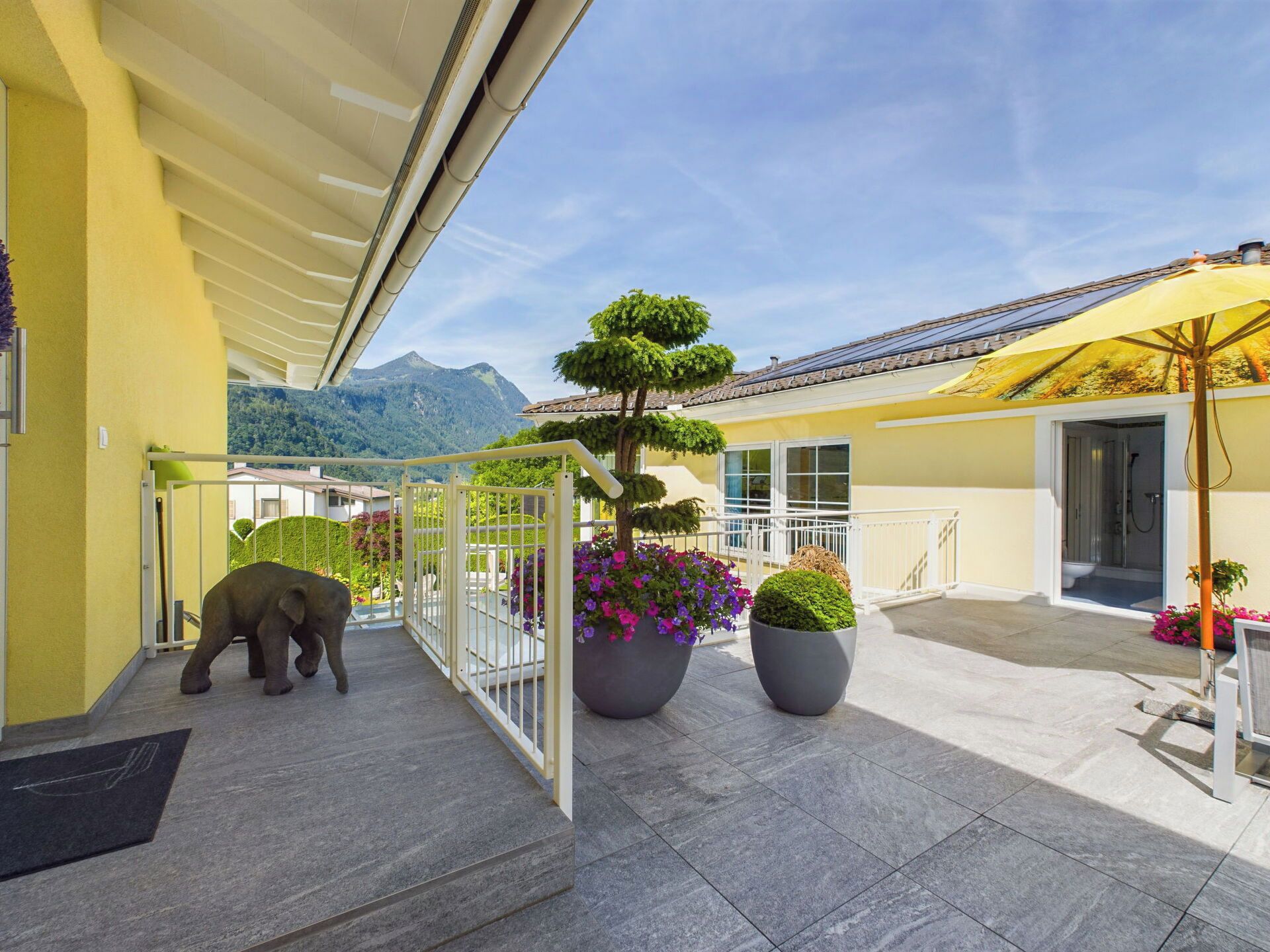Une cour d’hôtel avec vue sur la montagne, une petite statue d’éléphant et des plantes en pot.