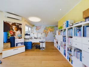 A well-lit room with a desk, computer, and bookshelf.