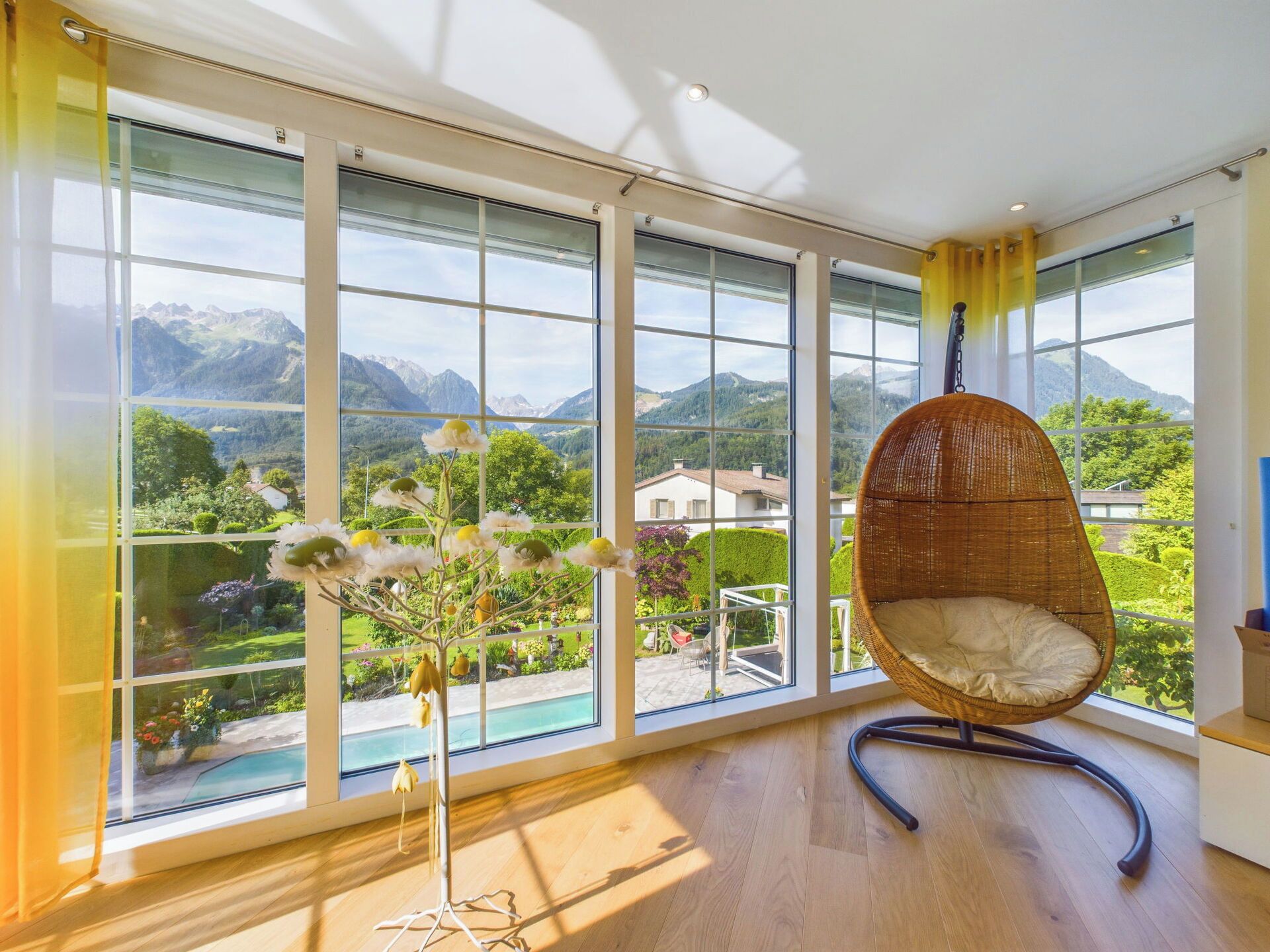 A room with large windows, a wicker chair, and a floor lamp.