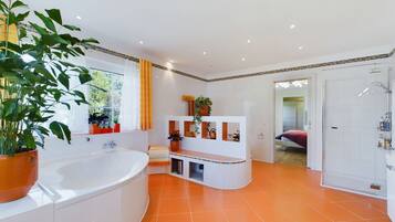 A modern bathroom with a large bathtub, a shower area, and a vanity with shelves.