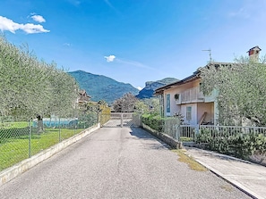 Eine Wohnstraße mit Häusern an beiden Seiten, blauem Himmel und Bergen im Hintergrund.