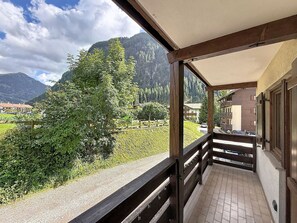Un balcon avec vue sur une montagne, un arbre et une route.