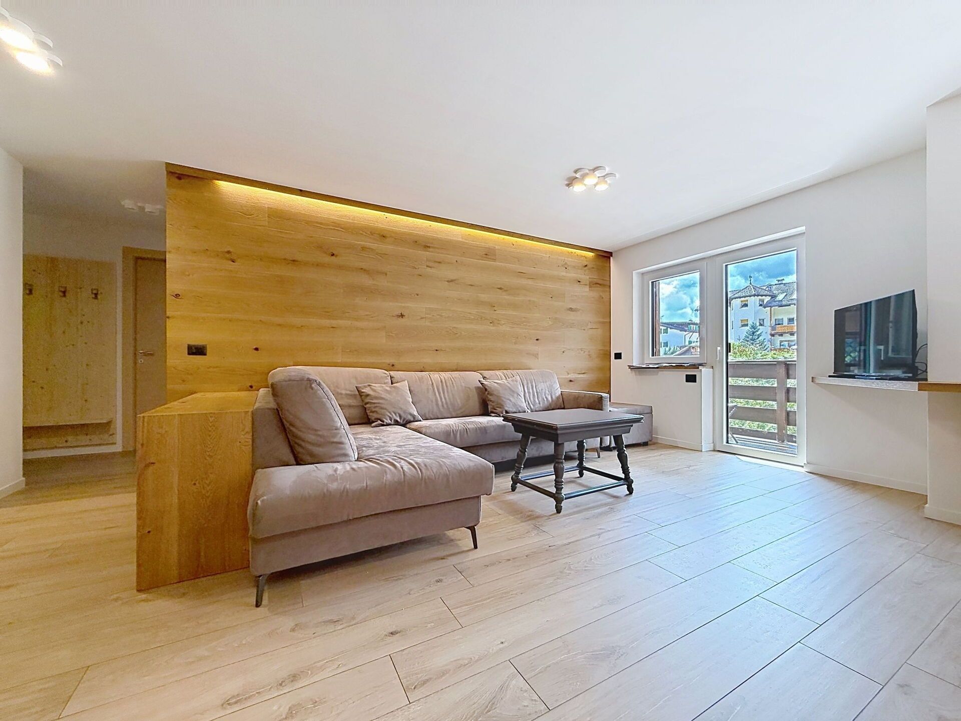 A modern living room with a wooden accent wall, a sofa, a coffee table, and a television.