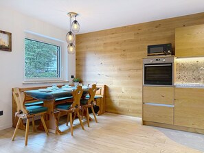 Eine moderne Küche mit Holzschränken, einem eingebauten Ofen und einem Essbereich mit Holztischen und einem Tisch.