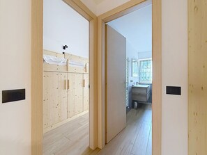 Ein Flur, der zu einem Schlafzimmer mit einem Holzschrank und einem Badezimmer mit Waschbecken und Spiegel führt.
