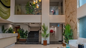En rummelig lobby med en central trappe, en receptionsdisk og et siddeområde med et sofabord.