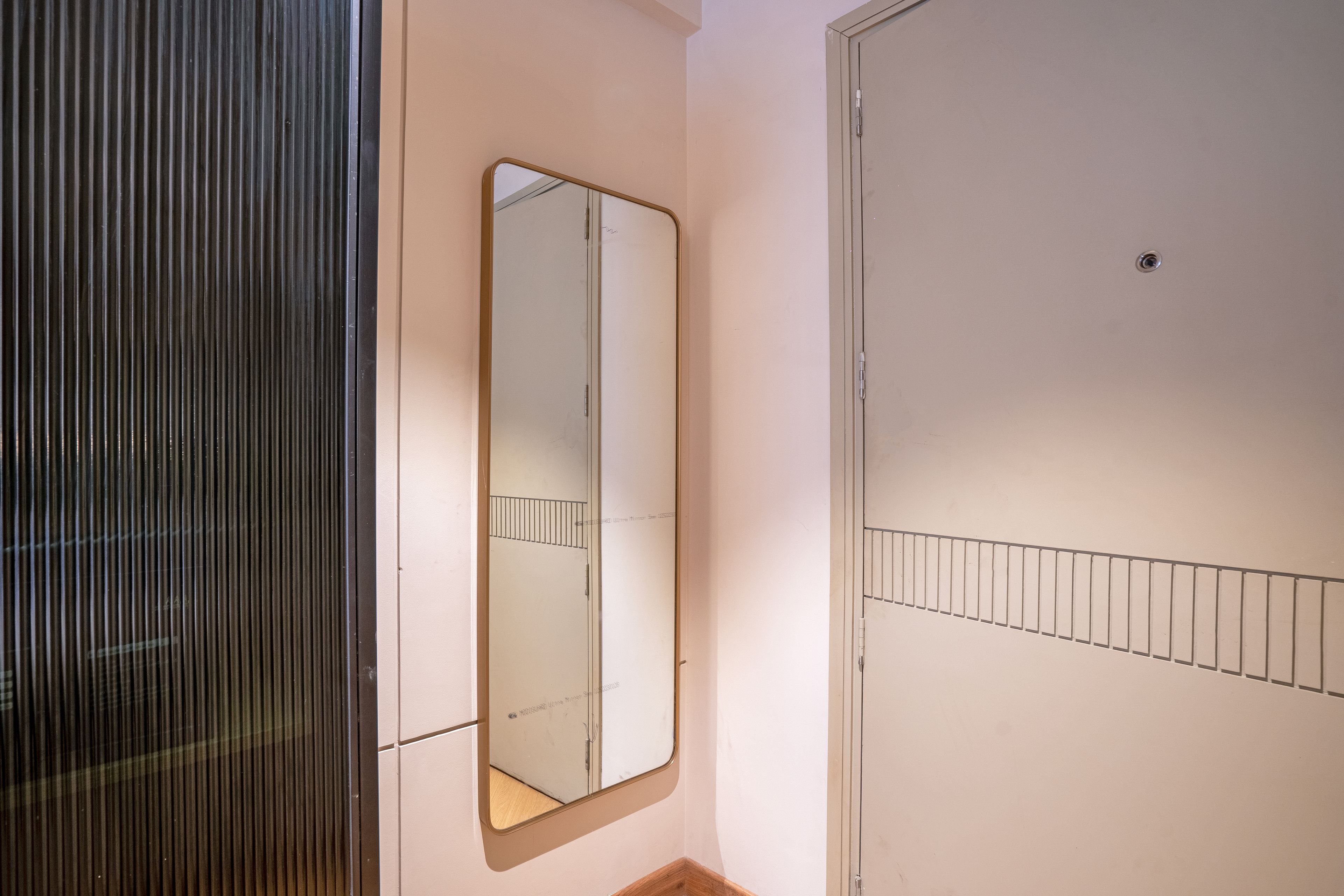 A room with a mirrored wardrobe, a door with a metal bar, and a wall-mounted shelf.