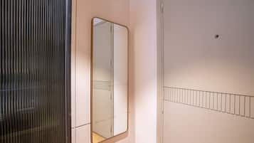 A room with a mirrored wardrobe, a door with a metal bar, and a wall-mounted shelf.