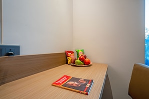 Ein Holznachttisch mit einem Buch mit dem Titel 'The World as I See It' und einer Fruchtschale mit Äpfeln und einer Mango.
