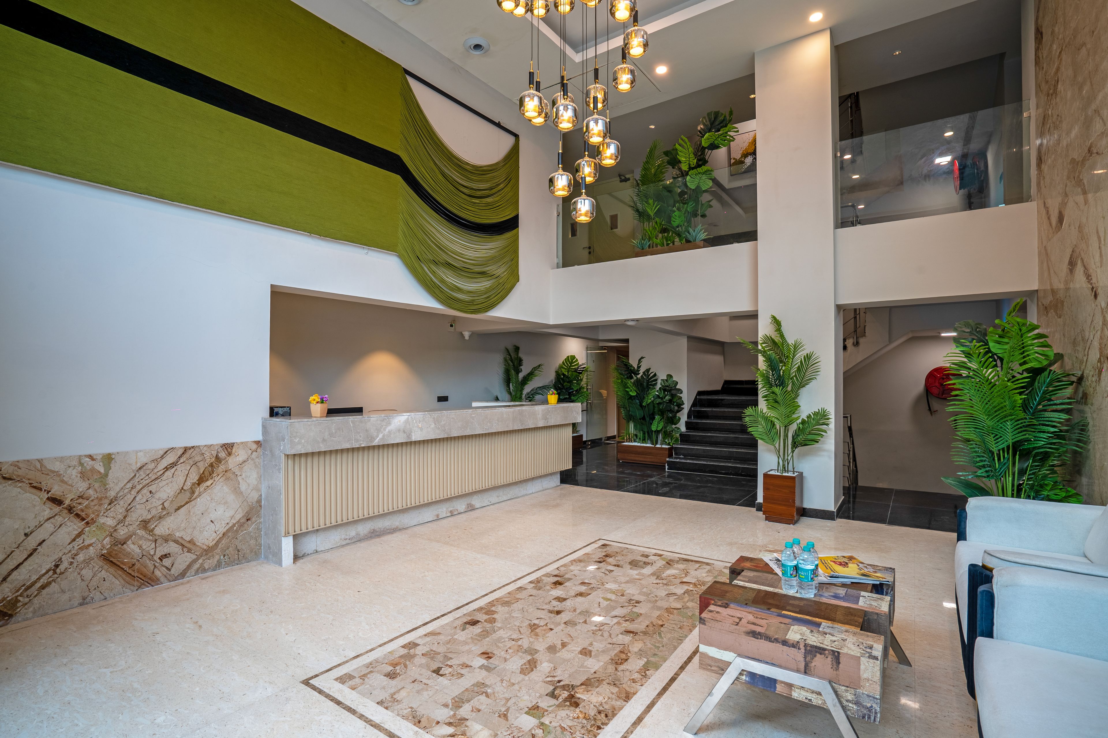 Un'ampia hall con reception, banco accettazione, scala e area salotto con tavolino.