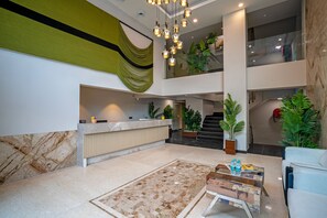 A spacious lobby with a reception desk, a check-in counter, a staircase, and a seating area with a coffee table. - Pause by Saltstayz- East of Kailash (New Delhi)