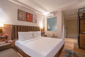 Ein Hotelzimmer mit einem großen Bett, Nachttischen, einer Wandlampe und einem Spiegel.