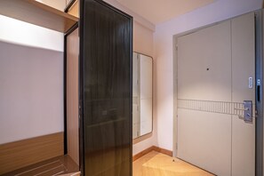 A hallway with a wooden floor, a glass door, and a white door with a metal handle.