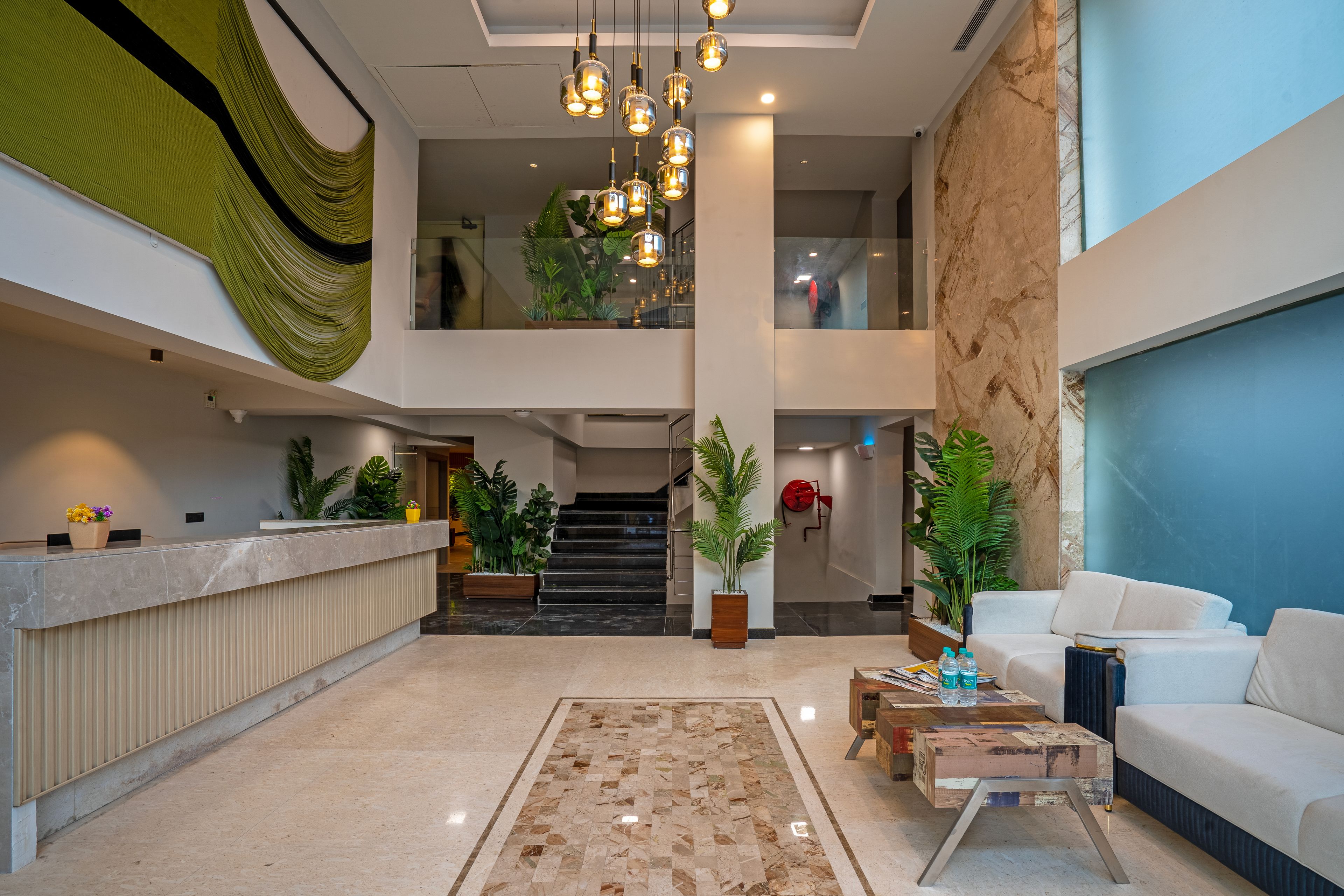 A spacious lobby with a reception desk, a staircase, and a seating area with a sofa and coffee table.