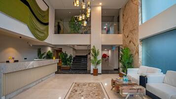 A spacious lobby with a reception desk, a staircase, and a seating area with a sofa and coffee table.
