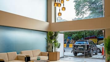 A spacious lobby with a high ceiling, a large window, a sofa, a coffee table, and a hanging light fixture.