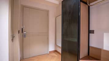 A room with a closed door, a wooden bench, and a wall-mounted mirror.