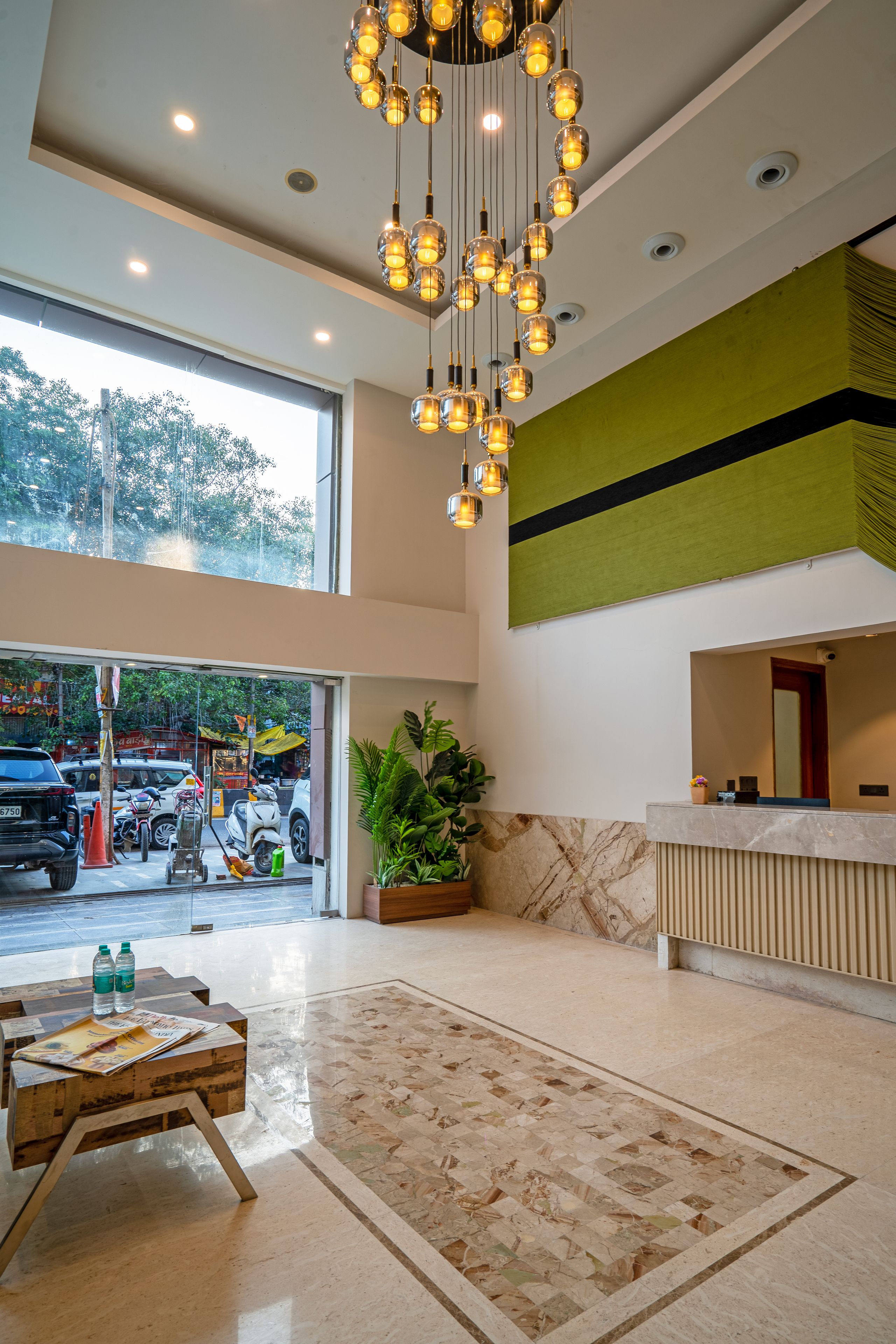 A hotel lobby with a reception desk, a large window, a hanging light fixture, and a reception counter.