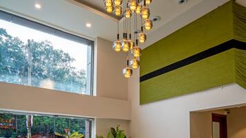 A hotel lobby with a reception desk, a large window, a hanging light fixture, and a reception counter.