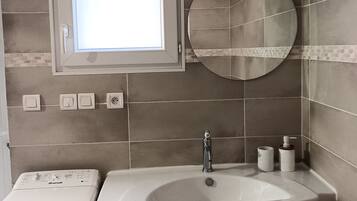 Une salle de bain avec un lavabo intégré, un miroir, une fenêtre et des toilettes.