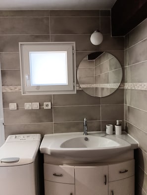 Une salle de bain avec un lavabo intégré, un miroir, une fenêtre et des toilettes.