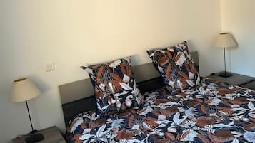 Une chambre à coucher avec un lit, deux tables de chevet, une lampe et un élément décoratif mural.