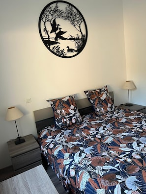 Une chambre à coucher avec un lit, deux tables de chevet, une lampe et un élément décoratif mural.