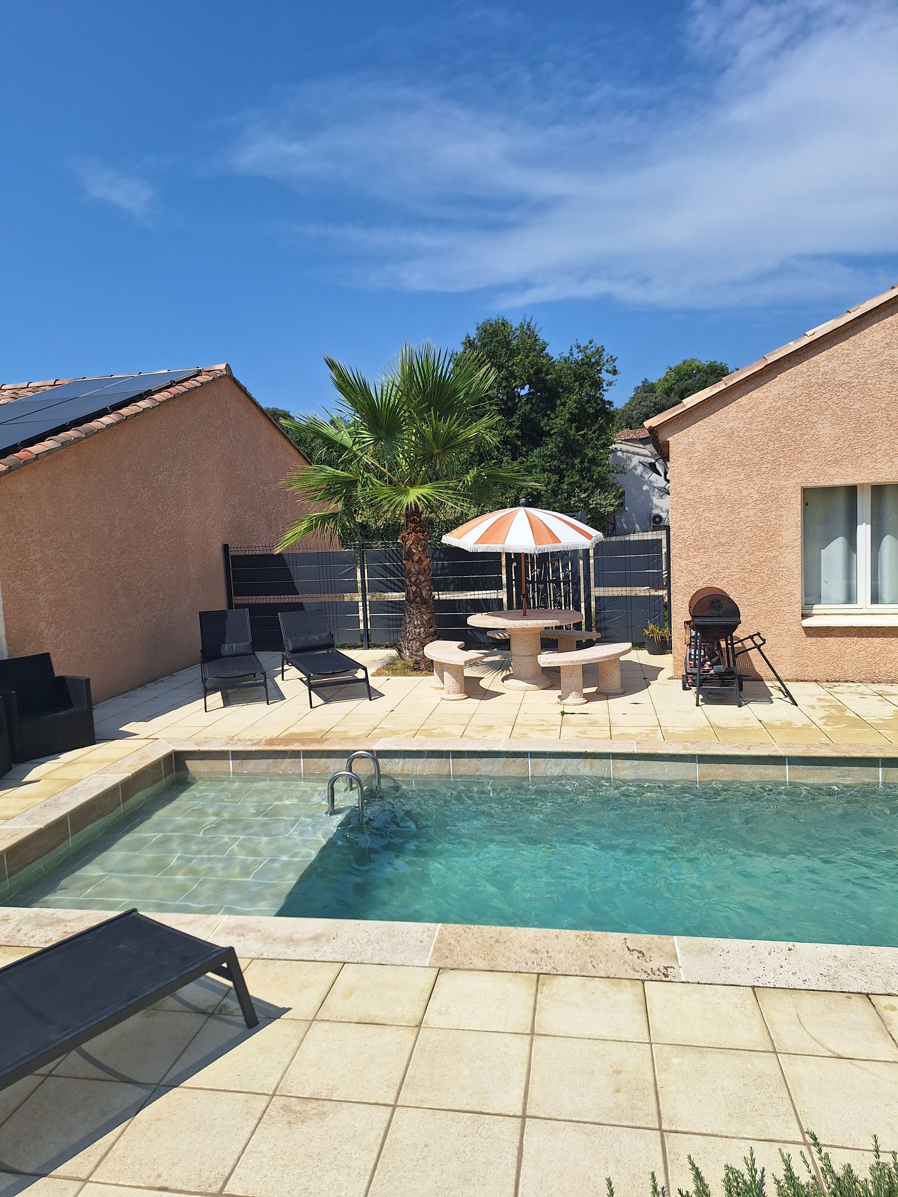Une piscine, des chaises longues, un barbecue et une table avec des chaises.
