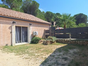 A house with a tiled roof, a stone wall, and a gate.