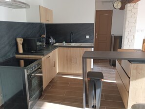 Una cocina moderna con encimera negra, armarios de madera, estufa de acero inoxidable y un cubo de basura.