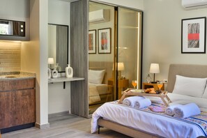 Ein Hotelzimmer mit Bett, Nachttisch, Lampe und einer Schiebetür zum Badezimmer.
