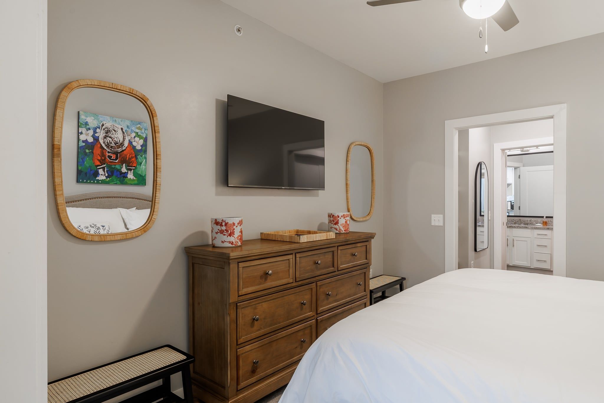 A bedroom with a bed, a dresser, a television, and a mirror.