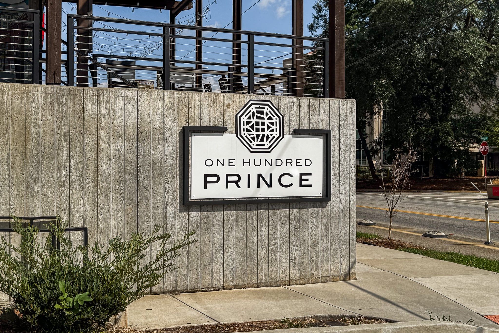 Een bord met de tekst 'ONE HUNDRED PRINCE' en een geometrisch logo.