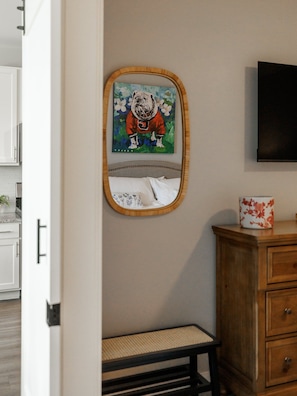A room with a bed, a wooden cabinet, a television mounted on the wall, and a framed picture of a bulldog. - The Athens Social - walk to downtown! (Athens)