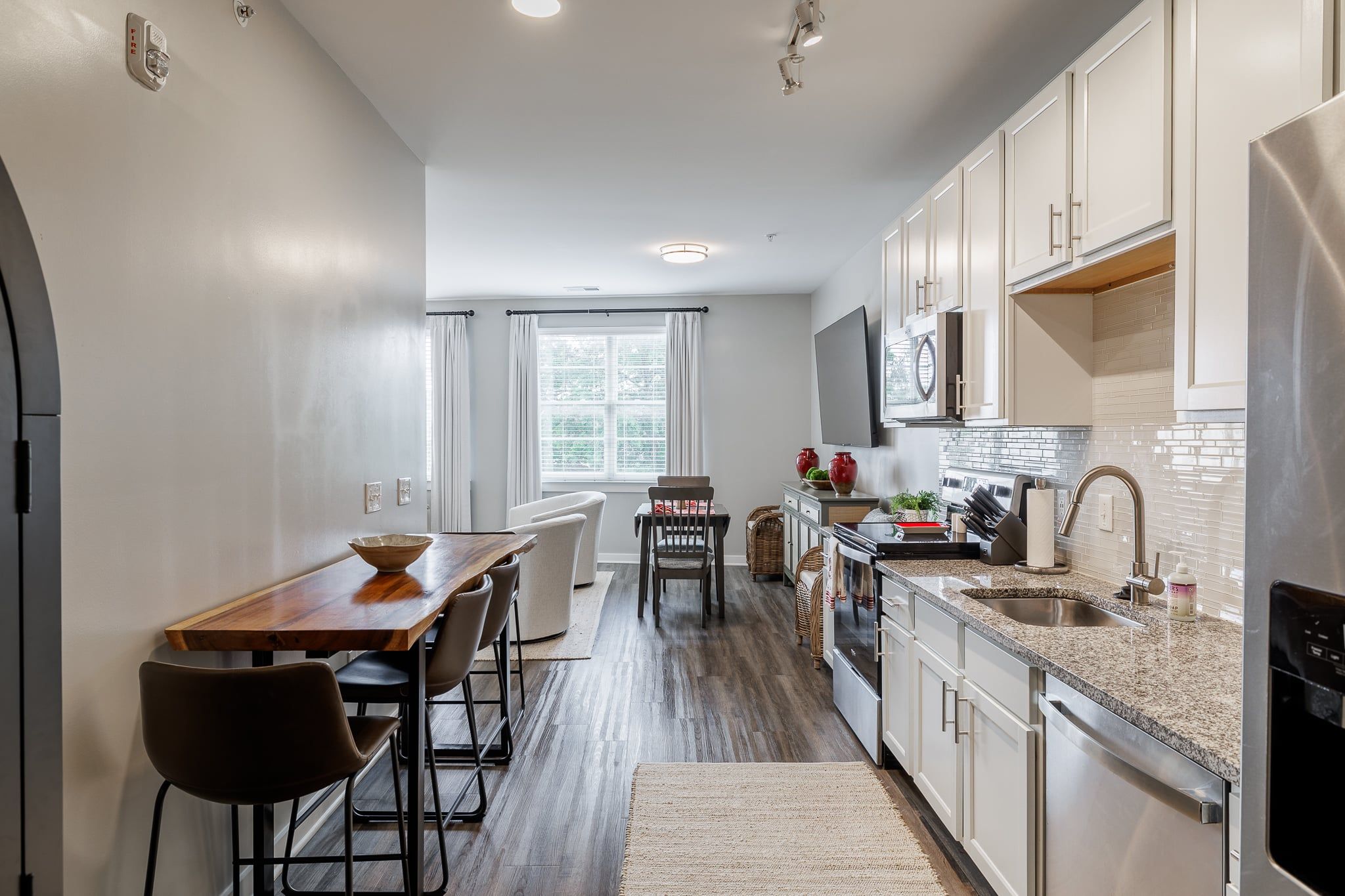 A modern kitchen with a dining area, wooden table, and chairs.
