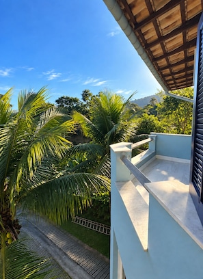 Un balcon offrant une vue sur une végétation luxuriante et une montagne lointaine.