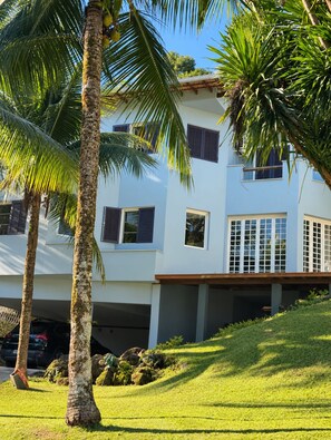 A modern two-story building with a flat roof, large windows, and a covered driveway. - A different Rio experience | Exclusive house with 4 suites near Barra. (Rio de Janeiro)